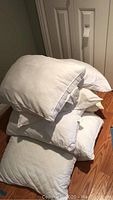 Stack of 6 white pillows showing quilted and plain designs.