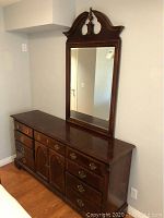 Photo showing full front view of large wooden dresser with attached mirror featuring carved wood frame with arch design.
