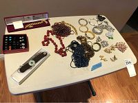 Full view of the assortment of costume jewelry laid out on a table including necklaces, bracelets, earrings, and brooches.