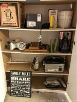 Four shelves filled with assorted kitchenware and household items including coffee maker, coffee urn, light bulbs, decorative pieces, dish rack, and slow cooker.