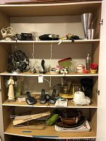Four shelves of assorted household items including cordless phones, kitchen appliances, decor, power cords, and containers.