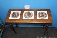 Overview photo showing entire wooden side table with three square decorative ceramic tiles on top.