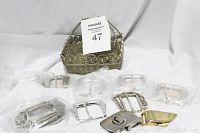 Wire basket containing 11 assorted belt buckles in front including ornate Nadim USA Richard Stump buckle.