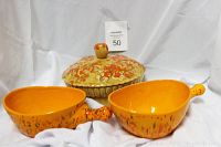 Three vintage serving bowls: two orange speckled bowls with handles and one covered Nasco bowl with an autumn theme.