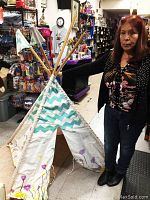 Photo of children's playhouse teepee set up indoors with a woman standing beside it.