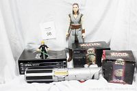 Photo showing all six items including the small Luke Skywalker figure, Rey 11-inch figure, Lott Do Do figure, Queen Amidala's Royal Starship in box, Laser Light toy, and Star Wars Trilogy DVDs.