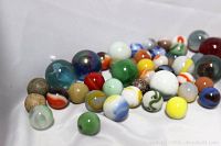 Close-up photo showing a variety of colorful vintage marbles including solid colors and swirled patterns.