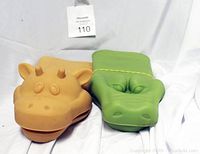 Orange giraffe and green alligator animal-shaped oven mitts side by side on white backdrop
