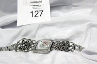 Full length photo of Ed Hardy watch laid flat showing the triple chain link wide band and rectangular face with flower design.