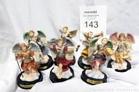 Front and side view of seven angel statuettes arranged on white background with visible name plates