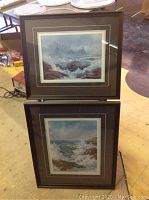 Two framed prints, one above the other, both depicting ocean scenes with waves and warships. Frames are wooden with glass and show wear.