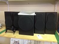Four bookshelf speakers and one subwoofer on shelf with one bracket in front