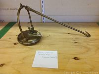 Brass oil lamp on wooden surface with note describing it as a French wale oil miner's lamp, possibly replica.