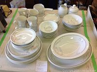 All dishes arranged on table showing complete set including platters, plates, bowls, cups, creamers, sugar bowl.