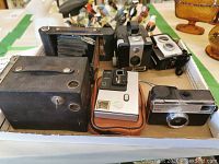 Photo showing six vintage cameras in a box, including folding bellows and box styles.