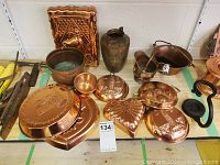 View of copper items including wall decor, pots, vase, pitcher, and copper molds in various shapes and sizes arranged on a table