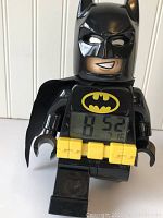 Front view of Lego Batman figure with digital clock display and yellow belt buttons.
