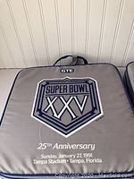 Close-up of Super Bowl XXV 25th Anniversary seat cushion showing logo, date, and Tampa Stadium location