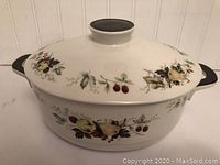 Wedgwood Wild Strawberry Dutch oven with lid, showing fruit and floral pattern on white ceramic and black handles.