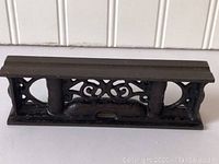 Side view of vintage cast iron level showing ornate cutouts and two vertical columns framing the vial.