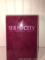 Front view of the maroon DVD box with embossed silver text 'Sex and the City The Complete Series'.