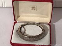 Sterling silver engraved bangle bracelet in an Amanda Smith jewelry box showing engraved floral and leaf patterns and safety chain.