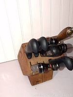 Side view of wooden knife block holding knives with black and wooden handles.