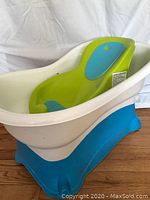 Front angle view of the baby bath tub with green infant support insert inside showing size and design.