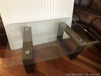 Full view of glass top coffee table with ribbed wood bases and metal fasteners.