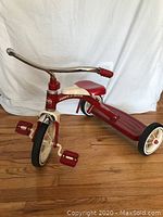 Front and side view of the Radio Flyer tricycle showing red pedals, cream and red frame with metal handlebars and red seat