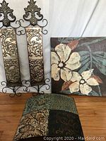Metal wall sconces with ornate detailing and floral canvas art with decorative cushions on a wooden floor