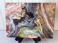 Full view of the acrylic pour painting showing the marbled swirls of color.