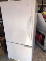 White Kenmore refrigerator in a room, showing exterior front view with door and handle.