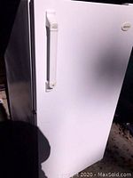 White Frigidaire upright freezer, full view showing front door and handle.