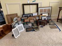 Photo showing 53 assorted photo frames of various sizes and styles laid out on carpet.