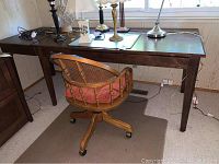 Photo of wooden desk with various lamps and objects on top, showing desk surface and legs.