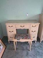 Cream painted wooden desk with multiple brass-handled drawers, vintage style.