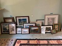 Wide view showing all 16 pieces of framed wall art arranged on floor leaning against wall, diverse sizes and styles