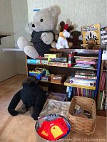 Large teddy bear and various stuffed animals on shelf with board games and puzzles below