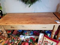 Larger natural wood table top and leg view showing wood grain and wear.
