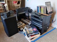 Front view showing stereo stack, speakers, cameras, CDs and VHS tapes