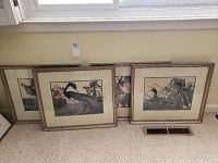 Four framed bird waterfowl prints leaning against wall under window