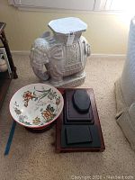 Full view of white ceramic elephant stool, floral ceramic bowl, and four wooden plant stands.