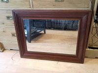 Full view of the front of the solid wood mirror showing rectangular design and glass mirror surface with visible wear spots.