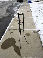 Full view of the cast iron umbrella and cane stand on the sidewalk showing height and structural details