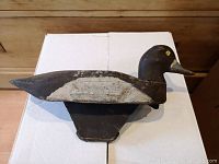 Top view of primitive hand-carved wooden duck decoy showing paint wear and overall form.