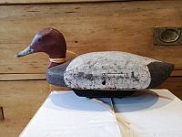 Side view of the wooden duck decoy showing general shape, paint condition, and a rubber band around its neck.