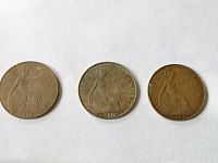 Three UK One Penny coins dated 1913, 1920, and 1921 laid out showing front with Britannia design.