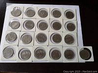 Top view of 25 Canada dollar coins from 1968 to 1986 placed in protective casings arranged on a tray.