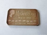 Front view of silver bar showing 'Mother's Day May 12 - 1985', silhouette profile, floral design, and purity stamp.